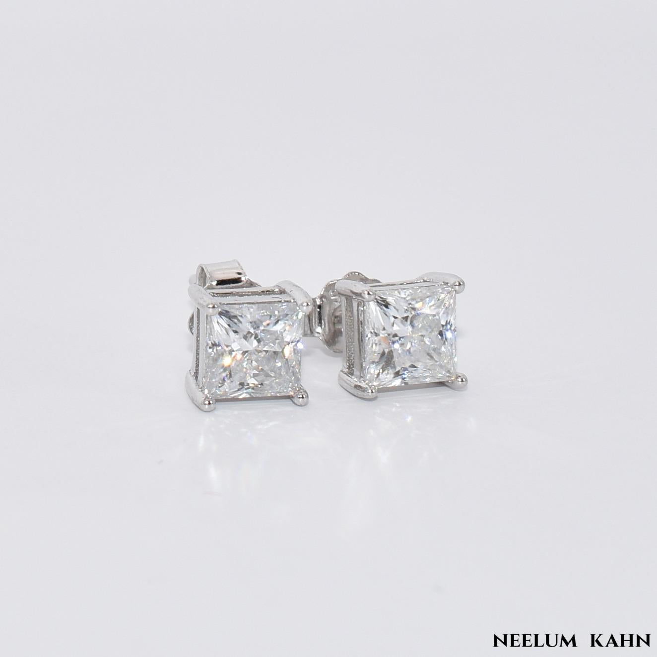 Pair of  1ct Moissanite diamond stud earrings on a light gray background with 'Neelum Kahn' branding.