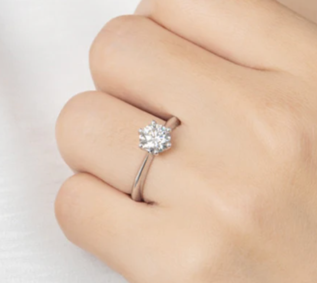 1ct Moissanite Diamond Ring, 925 Sterling Silver, 18K Gold Plated, Round Cut on a finger against a light background